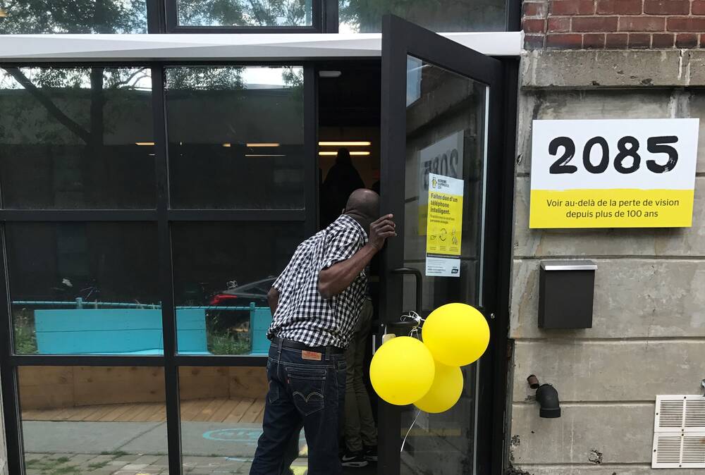 Un homme entre dans le Hub d'INCA. La porte est décorée de ballons jaunes