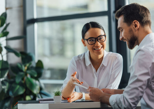 An Asian woman pointing at something on a piece of paper held by a white man