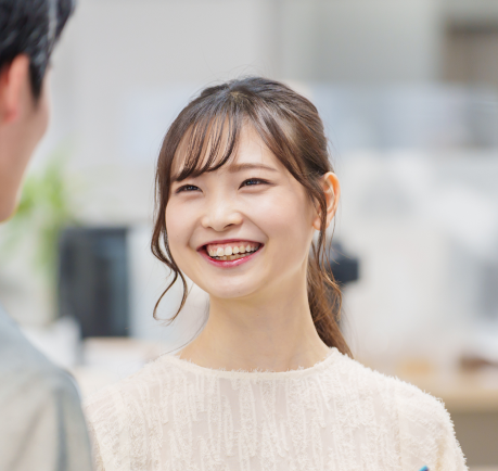 Une jeune femme asiatique souriante qui discute avec un autre homme. 