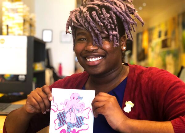 A joyful black woman holding a paper with an illustration of an octopus