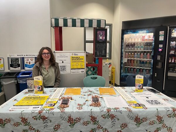 Erin sits at a table with several CNIB materials and brochures while at Camosun College