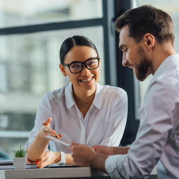 An Asian woman pointing at something on a piece of paper held by a white man